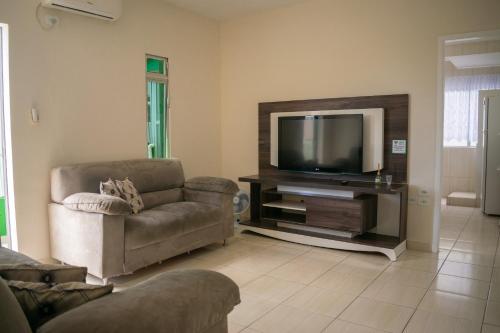 a living room with a couch and a television at Edifício Iris - Bombinhas in Bombinhas