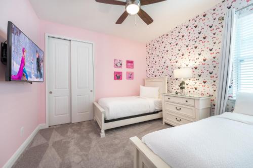 ein Schlafzimmer mit zwei Betten und einem Deckenventilator in der Unterkunft Elegant Home Near Disney With Private Pool, Foosball Table, Themed Rooms And Waterpark & Resort Access At Encore Resorts Reunion - 365Sf in Kissimmee