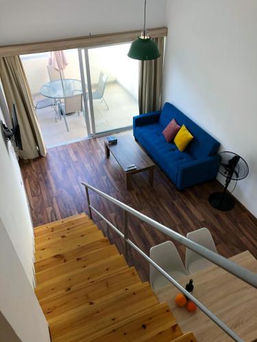 ein Wohnzimmer mit einem blauen Sofa und einer Treppe in der Unterkunft Cozy Loft Apartment in Ayia Napa
