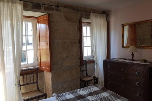 a bedroom with a bed and a dresser and windows at A casinha do beco in Gouveia