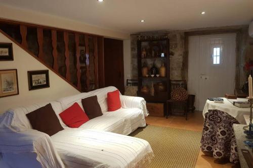 a living room with a white couch with red pillows at A casinha do beco in Gouveia