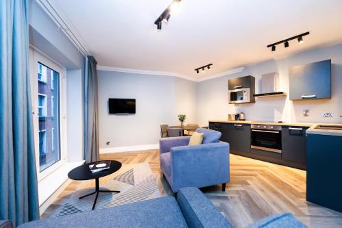 a living room with a blue couch and a kitchen at Staycity Aparthotels, Dublin, Christchurch in Dublin