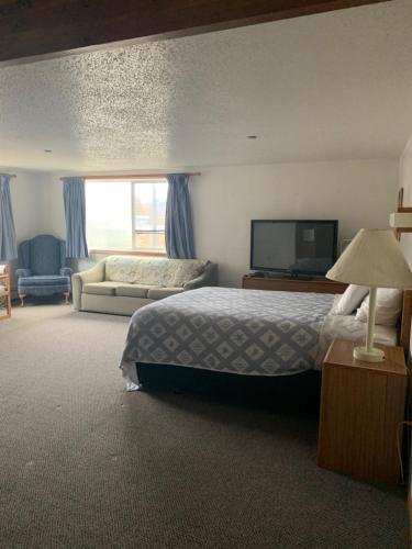 een slaapkamer met een bed, een bank en een televisie bij Marina Motel in Seward