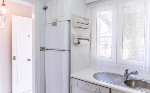 uma cozinha branca com um lavatório e um frigorífico em Estupendo Adosado Urbanizacion Hoyo 12 Novo Sancti Petri em Chiclana de la Frontera