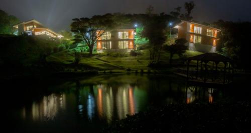 a house at night with a reflection in the water at Burbi Lake Lodge Monteverde in Monteverde Costa Rica