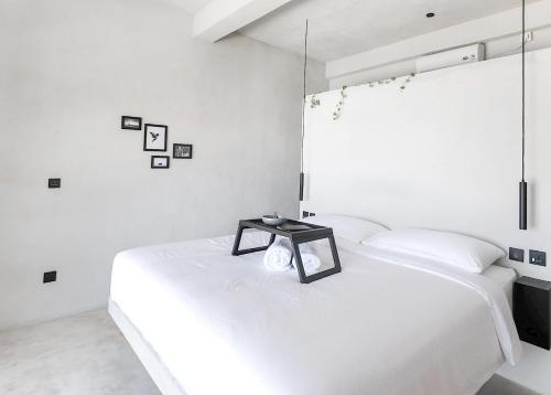 a white bedroom with a bed with a table on it at OCEANNA - Uluwatu, Bali in Uluwatu