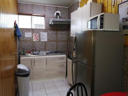 a kitchen with a stainless steel refrigerator and a sink at Hostal Copiapó Puerto Montt in Puerto Montt