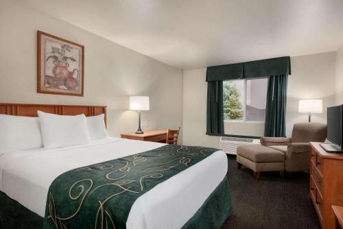a hotel room with a bed and a chair at Travelodge by Wyndham Clinton Valley West Court in Clinton