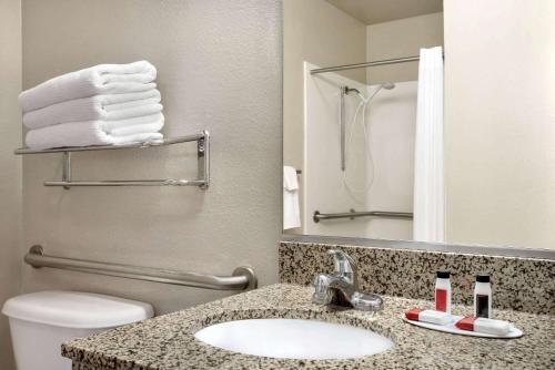 a bathroom with a sink and a toilet and a mirror at Travelodge by Wyndham Clinton Valley West Court in Clinton