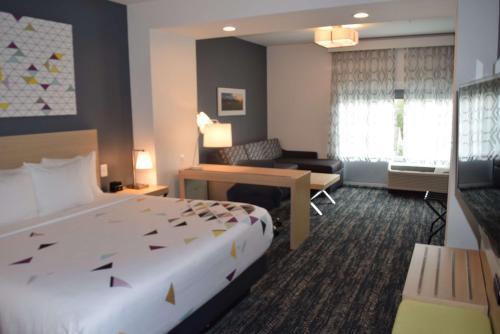 a hotel room with a large bed and a desk at La Quinta Inn & Suites by Wyndham Manassas, VA- Dulles Airport in Manassas