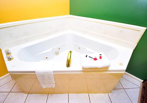 La salle de bains est pourvue d'une baignoire dans des tons vert et jaune. dans l'établissement Super 8 by Wyndham Searcy AR, à Searcy