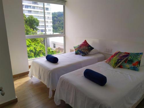 two beds in a room with a large window at Departamento con Preciosa Vista al Mar en Acapulco Diamante in Acapulco