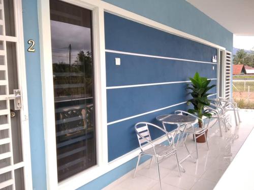 un patio con sillas y una mesa en una pared azul en Sacha Homestay en Baling