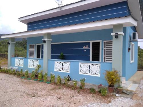 una casa azul con plantas delante en Sacha Homestay en Baling