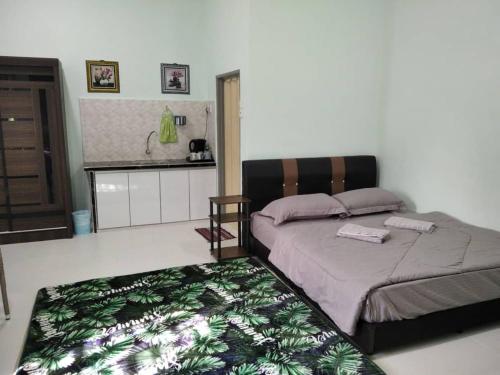 ein Schlafzimmer mit einem Bett mit einer grünen Decke darauf in der Unterkunft Sacha Homestay in Baling