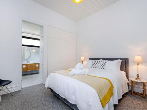 a white bedroom with a large bed and a window at Red Door at Wishart in Port Fairy