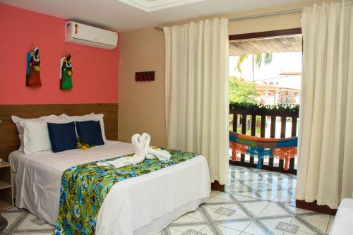 a bedroom with two beds and a balcony at Pousada Velosmar in Porto De Galinhas
