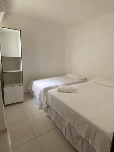 a bedroom with two beds and a dresser and a mirror at Mellim Residence in Maragogi
