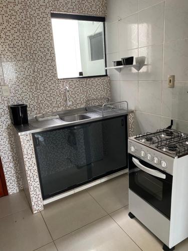 uma cozinha com um fogão e um lavatório em Mellim Residence em Maragogi