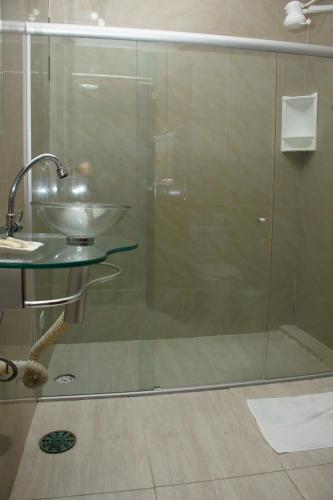a bathroom with a glass shower with a sink at Pousada Velosmar in Porto De Galinhas