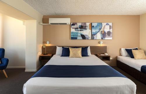 a hotel room with a large bed and a blue chair at The Metropolitan Spring Hill in Brisbane