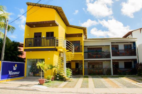 a yellow building with a staircase in front of it at Pousada Velosmar in Porto De Galinhas