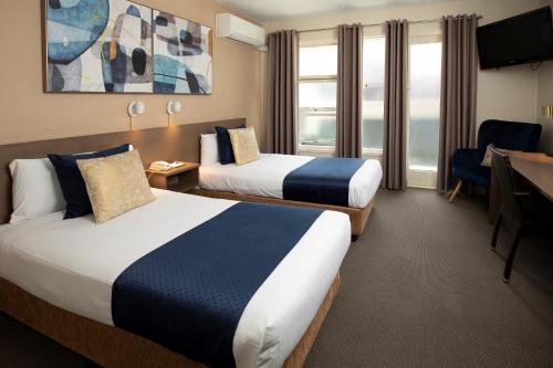 a hotel room with two beds and a desk at The Metropolitan Spring Hill in Brisbane