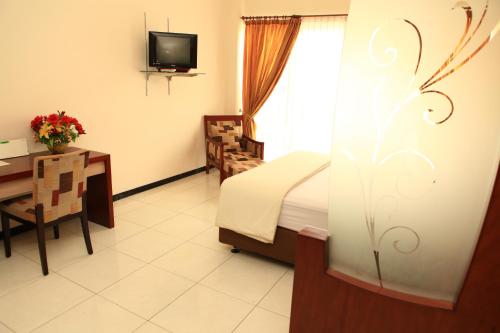 a bedroom with a bed and a desk and a television at Arya Graha Semarang in Semarang
