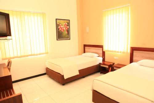a hotel room with two beds and a television at Arya Graha Semarang in Semarang