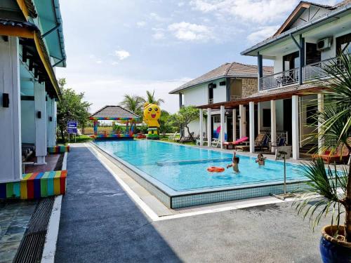 a large swimming pool with people in a resort at Alia Residence Business Resort in Kampung Padang Masirat