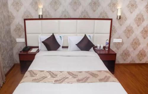 a bedroom with a large white bed with two tables at Hillcrest Metro in Ooty