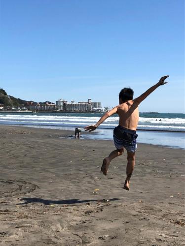 a young man jumping in the air on a beach at GOOD MORNING ZAIMOKUZA in Kamakura