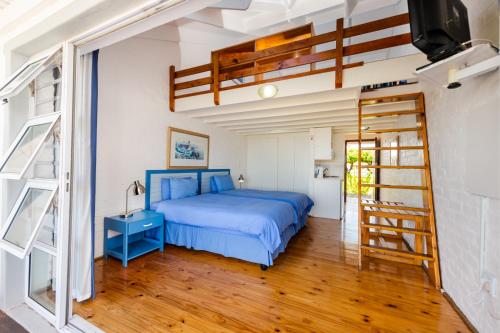 um quarto com uma cama azul e uma escada em Friday Island em Langebaan