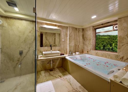 a bathroom with a tub and a sink at Sarovar Portico Gir in Sasan Gir