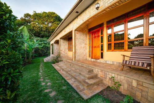 a brick house with a red door and a bench at Kisubi Forest Cottages in Entebbe