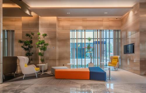 a lobby with chairs and a couch and a tv at Holiday Inn Express Linyi North New District by IHG in Linyi