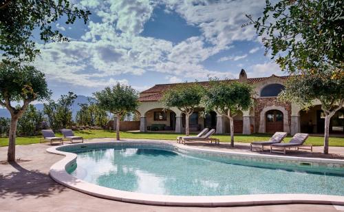 a swimming pool with chairs and a house at Cascioni Eco Retreat in Arzachena