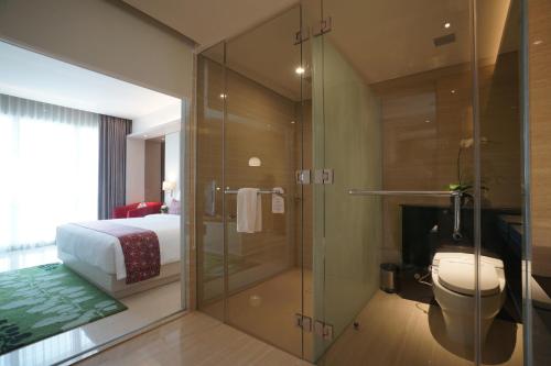 uma casa de banho com um chuveiro, um WC e uma cama em The Margo Hotel em Depok