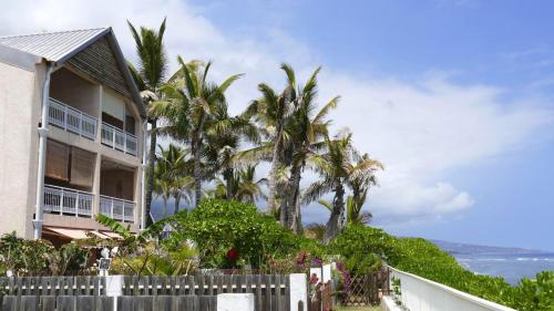 uma casa com palmeiras em frente ao oceano em Appartement d'une chambre avec vue sur la mer balcon amenage et wifi a Les Trois Bassins a 1 km de la plage em Le Bois de Nèfles