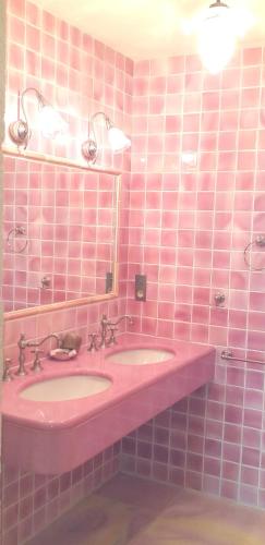 a pink tiled bathroom with two sinks and a mirror at Maison conviviale à Saint-Cybranet avec piscine partagée in Saint-Cybranet