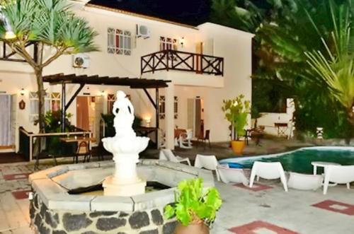 a house with a fountain in front of a pool at 2 bedrooms appartement with shared pool furnished terrace and wifi at Pereyber 1 km away from the beach in Pereybere