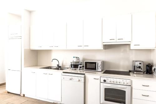 a white kitchen with white cabinets and appliances at Seaside Villa in Cap d'en Font with Private Pool in Cap d'en Font