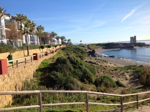 a beach with a fence next to the water at Bright apartment with sea view in Casares, 96 m², pool in Casares