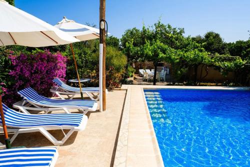 サン・ミゲル・デ・バランサットにある4 bedrooms villa with private pool enclosed garden and wifi at Sant Miquel de Balansat 5 km away from the beachのスイミングプールの隣の椅子とパラソル