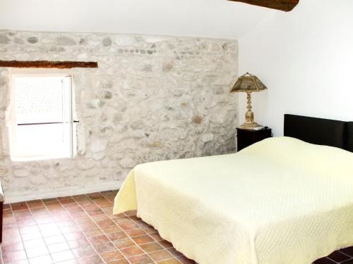 a bedroom with a bed and a stone wall at Maison de charme à Mollégès avec piscine privée in Mollégès