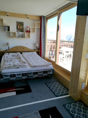 une chambre avec un lit et une grande fenêtre dans l'établissement Appartement convivial à La Plagne - 28 m² avec vue sur la montagne, à Mâcot La Plagne