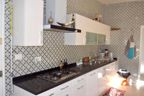 a kitchen with white cabinets and a black counter top at Charming Villa in Monastir with Private Pool in Monastir