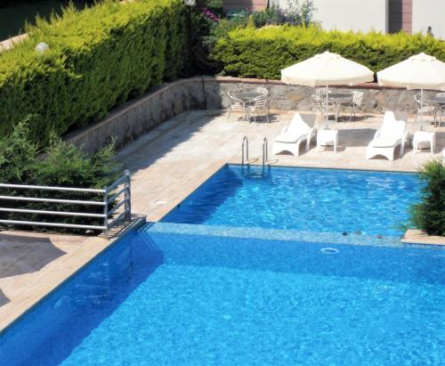 a swimming pool with chairs and umbrellas next to a pool at 3 bedrooms villa at TurgutreisBodrum 800 m away from the beach with sea view shared pool and enclosed garden in Karabağ