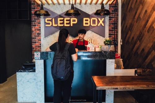 a woman standing in front of a sleep box at Sleepbox Hostel Suratthani in Suratthani