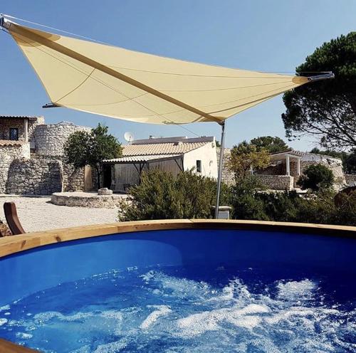 a white umbrella and a swimming pool with water at Charming Apartment with Jacuzzi and Sea View - Salve, 85 sqm in Salve